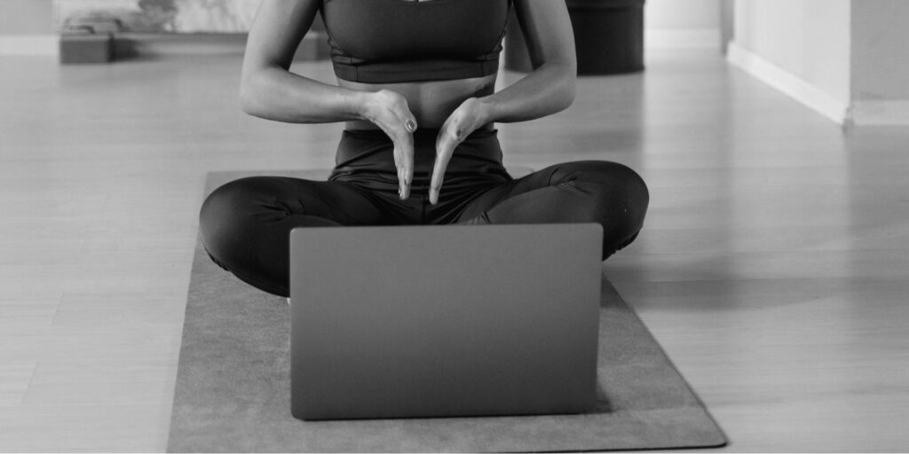Man sieht jemanden der Yoga vor einem computer unterrichtet